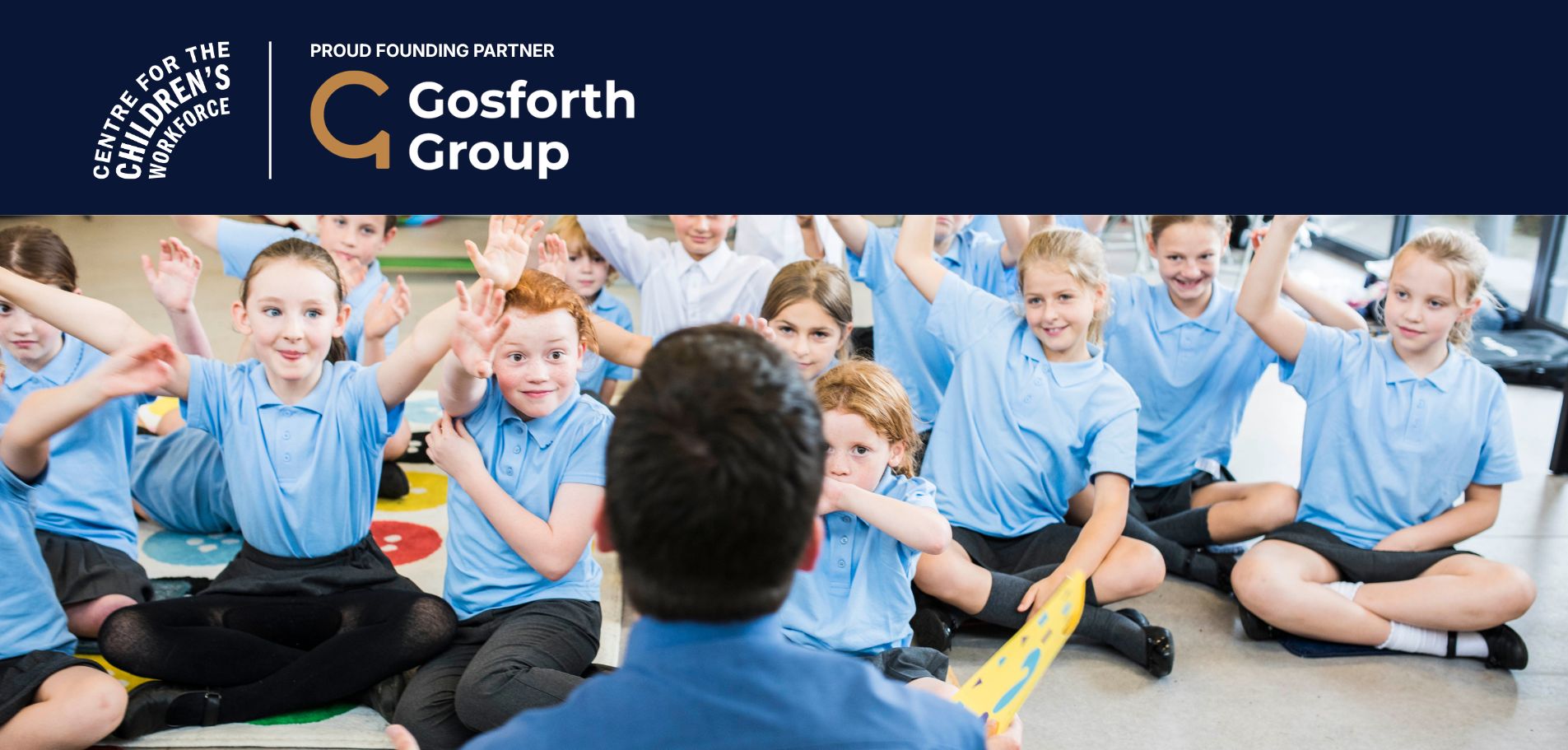 Male teacher sitting on the floor with a group of primary school pupils