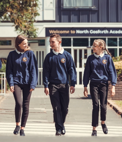 Three students walking in front of the academy entrance. 